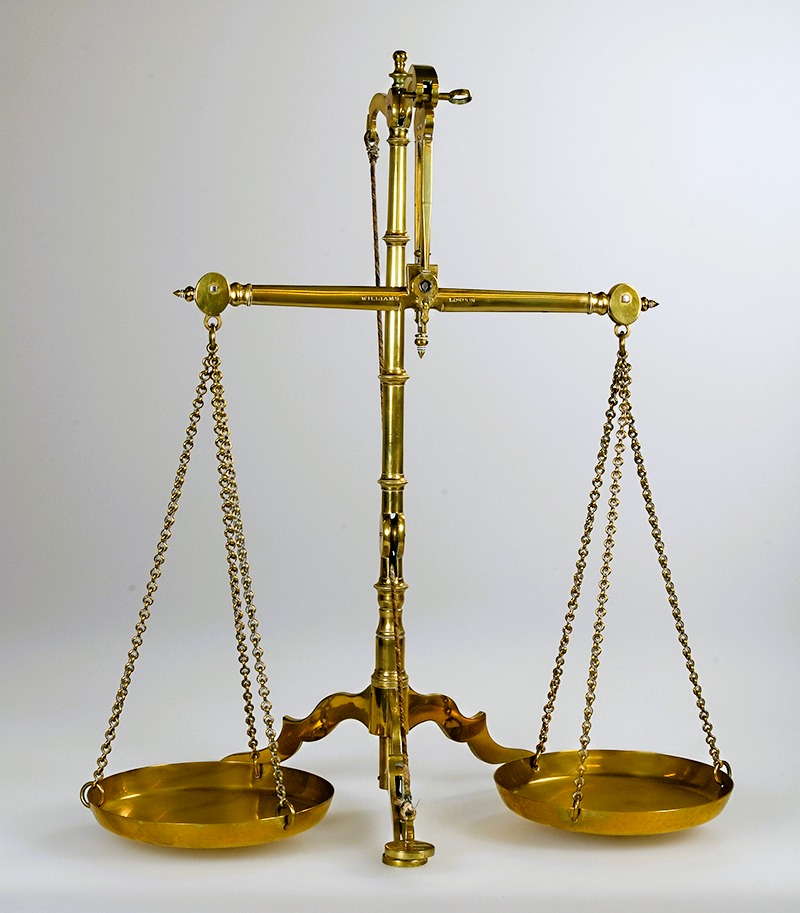 Balança antiga de latão dourado em equilíbrio, simbolizando a justiça, o direito e o equilíbrio orçamental da economia.